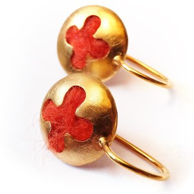 Goldene Ohrringe gefüllt mit roter Wolle