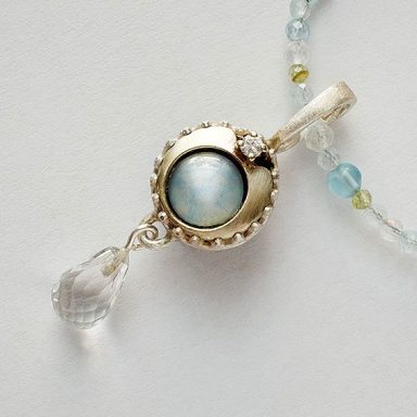 Weißgold-Anhänger mit Opal und Tropfenverzierung aus Bergkristall.