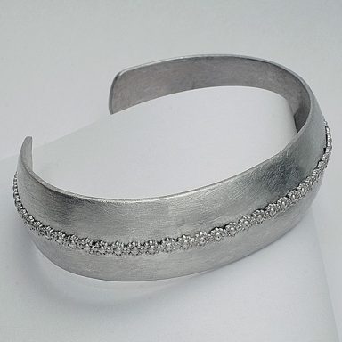 Silberner Armreif mit feiner Verzierung entlang der Mittellinie.